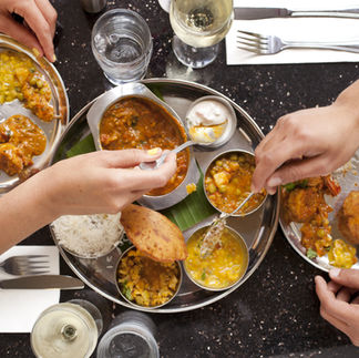 Repas convivial avec plusieurs mains partageant des plats colorés, symbole de plaisir, de partage et d’équilibre dans l’alimentation intuitive.