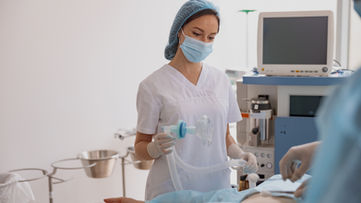 Ameliyathanede beyaz üniforma ve maske takan anestezi teknikeri.