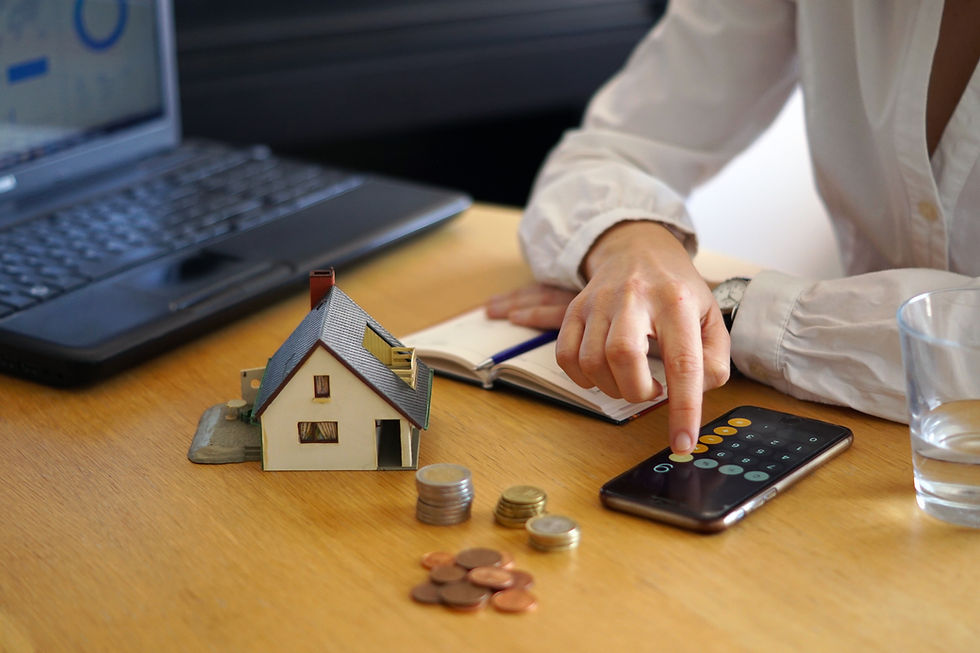 Hesap makinesi, para ve ev maketi ile Almanya’da sabit giderler ve bütçe kontrolü üzerinden finansal düzeni temsil eden görüntü.
