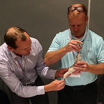 Two men building a prosthetic hand in a give back program