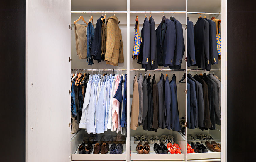 The inside of a bespoke wardrobe with clothes hanging