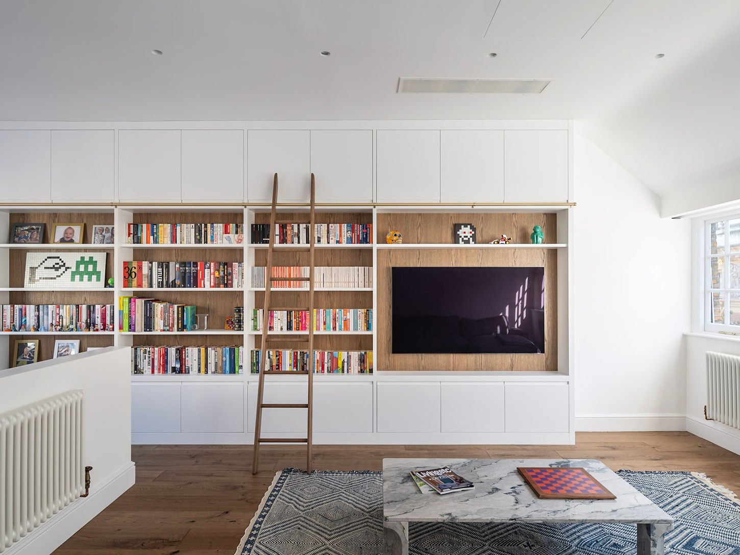 Bespoke media storage wall in London with integrated TV, oak shelving and concealed storage by Williams Ridout