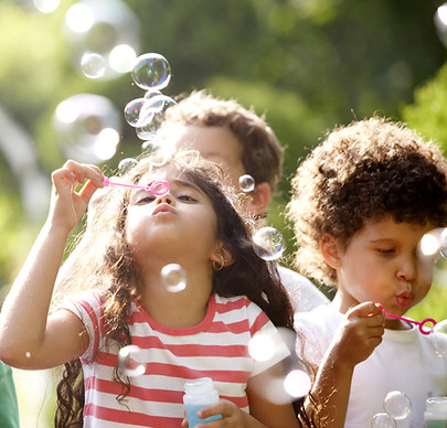 Niños felices jugando con burbujas de jabón en un parque