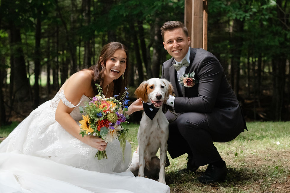Katie and Jack with their dog at their private estate wedding in Maine, featuring colorful wedding flowers