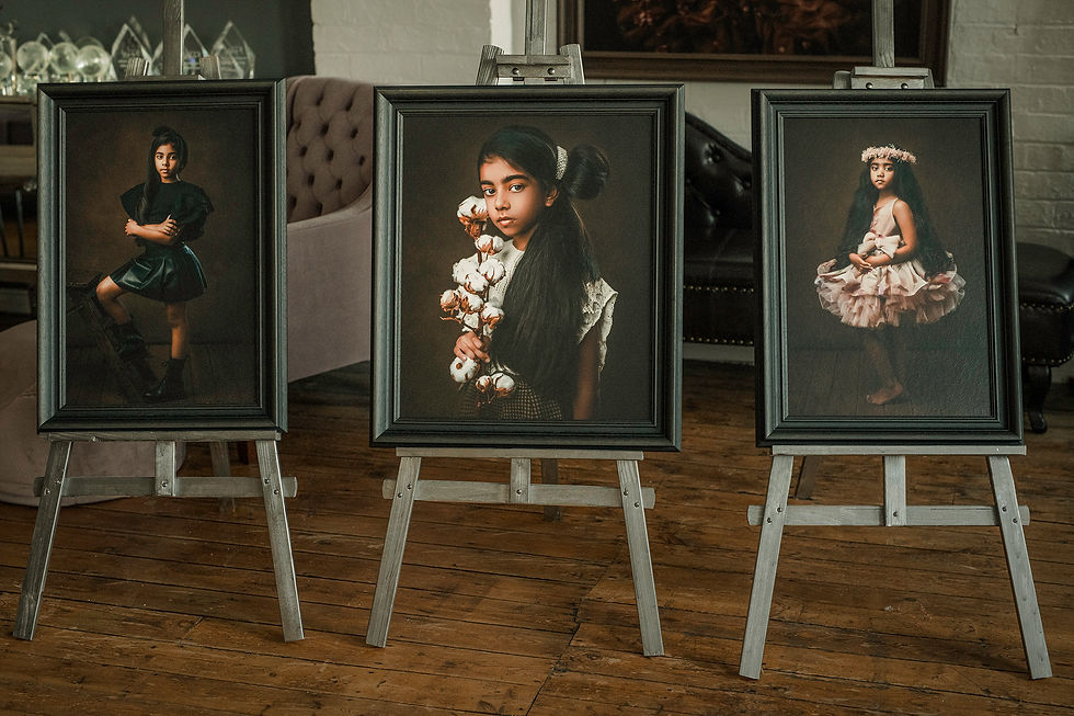 Three beautifully framed portraits displayed on easels in a studio setting, showcasing a young girl in various outfits. The images feature her in a stylish black dress, a floral crown, and a playful tutu, all set against rich, textured backgrounds that highlight her personality and charm.