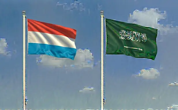 The flag of Luxembourg paired with the Saudi flag with a cloudless sky background for tourism.