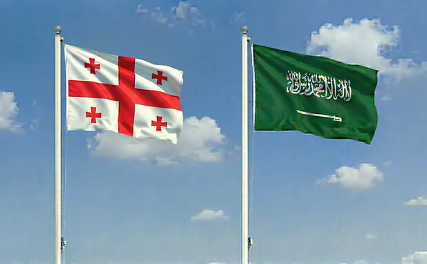 Flags of Georgia and Saudi Arabia side by side under a sunny sky for online visa portal imagery.