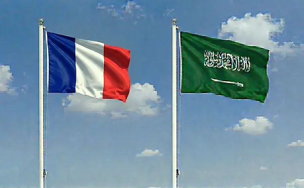 French and Saudi Arabian flags waving together in a clear sky, illustrating e-tourist visa connections.