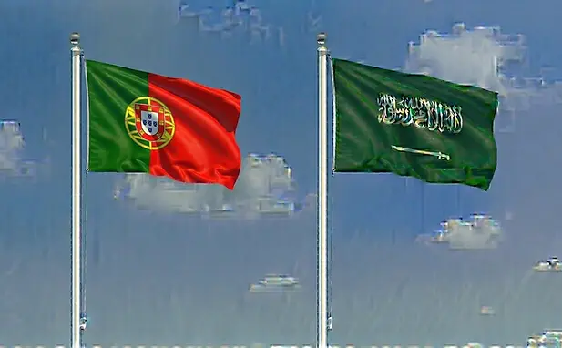 The flag of Portugal paired with the Saudi flag in a clear blue sky representing travel to Saudi Arabia.