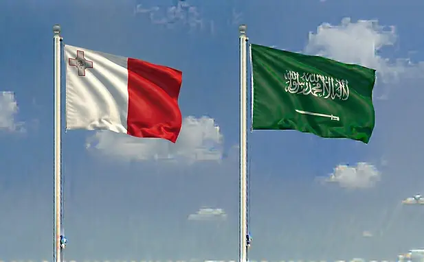 The Maltese flag alongside the Saudi Arabian flag under a sunny cloudless sky for e-visa processing.