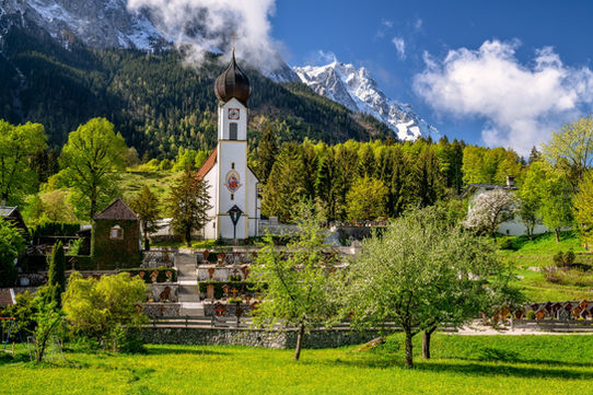 Zugspitzdorf Grainau in Oberbayern mit verschneiten Bergspitzen im Hintergrund