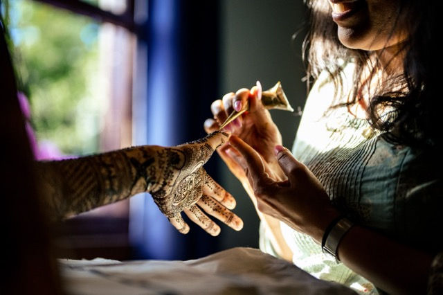 Henna artist applying henna designs on the bride using a natural henna cone