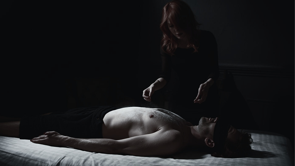 a woman stands behind a man lieing on a bed