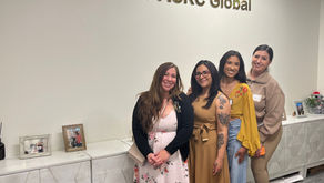 Cuatro mujeres que participan como Surrogates con ACRC Surrogacy posan juntas dentro de la oficina de ACRC Global, frente a un letrero que dice “Welcome to ACRC Global”, en un ambiente profesional y acogedor.
