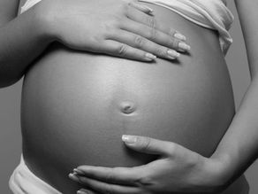 A surrogate mother holding her pregnant belly with love.