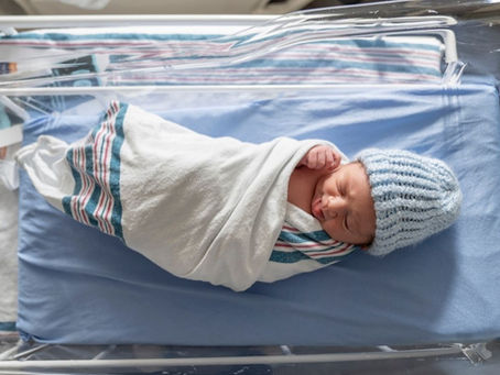 A newborn baby is wrapped up and put in a bassinet white he waits for his parents after delivery