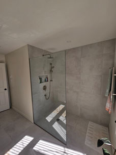 Grande douche sans porte avec panneau de verre et céramique grand format à Saint-Hubert