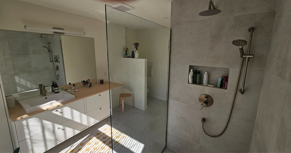 Vue d’ensemble de la salle de bain rénovée à Saint-Hubert avec douche vitrée et vanité sur mesure