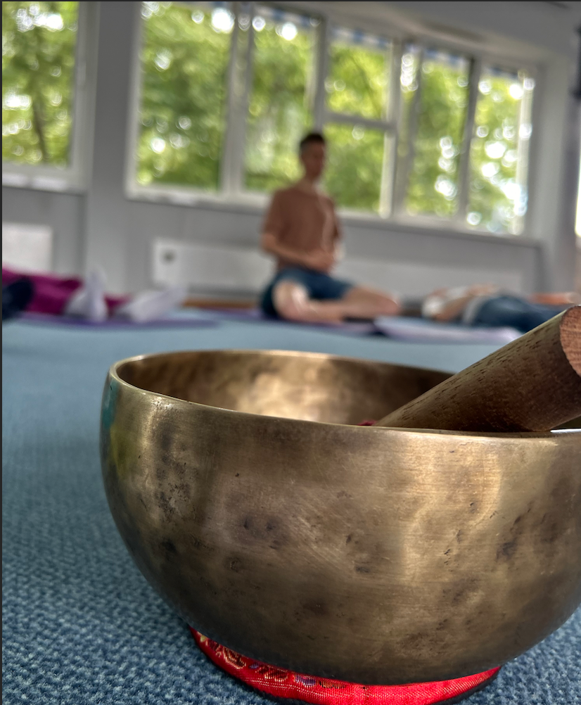 Klangschale im Vordergrund während einer Achtsamkeits- und Entspannungsübung in ruhiger Umgebung