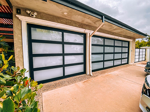 Sleek aluminum full-view glass garage door showcasing modern minimalist design, ensuring durability and a contemporary vibe on tan house