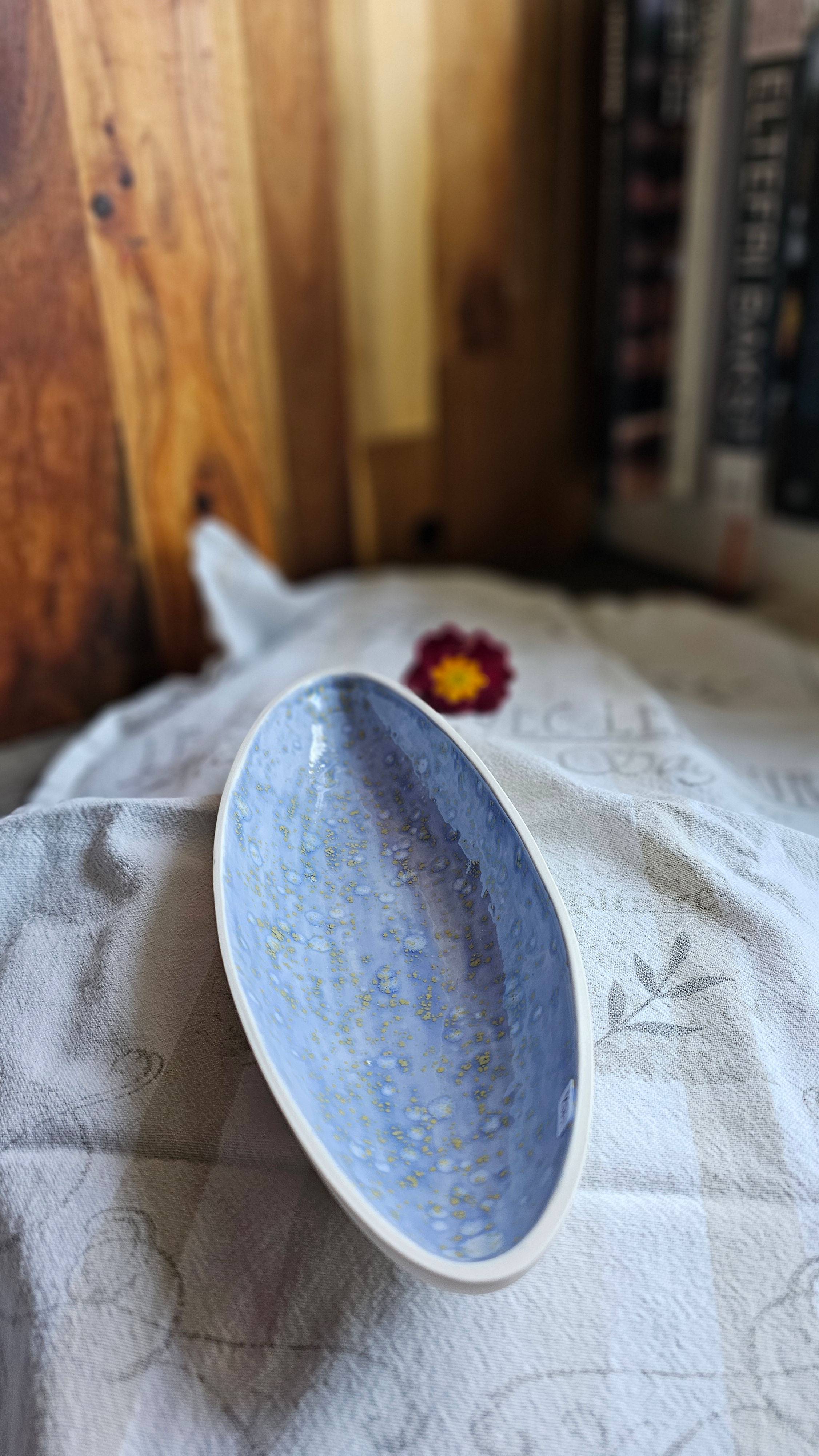 Porselensskål, båtforma. Lys blå med gule og kvite spettar.