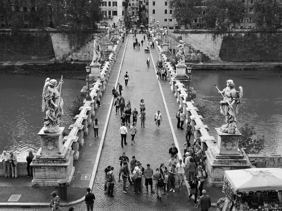 a black and white photo of people on a bridge