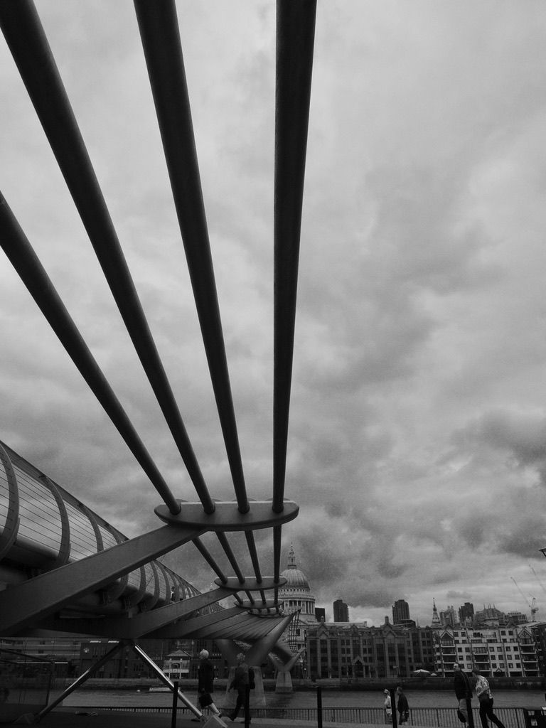 a black and white photo of a bridge with a dome in the background