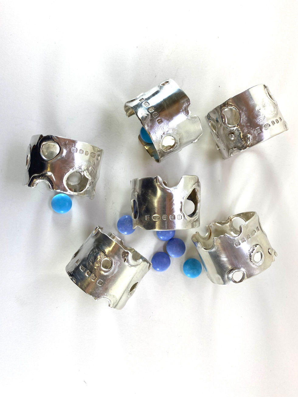 Sterling silver napkins rings, reticulated silver. Silver has 'moon crater' effect created by a technique 'reticulation'. The technique involves heating the silver or gold to up to ten times to oxidise the copper at the surface, then pickling to remove the oxide and leave a thin layer of pure metal on the surface. Silversmith David Salariya, silver maker,
hand-crafted silver, bespoke silver items, silver artisan, silver workshop.