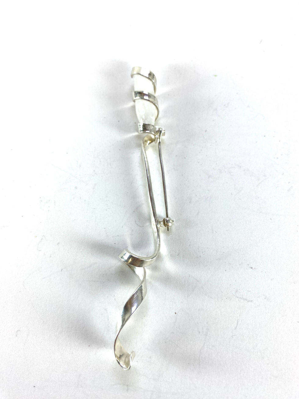 Sterling silver brooch, with moonstone contained in a silver spiral. Silversmith David Salariya, silver maker,
hand-crafted silver, bespoke silver items, silver artisan, silver workshop.