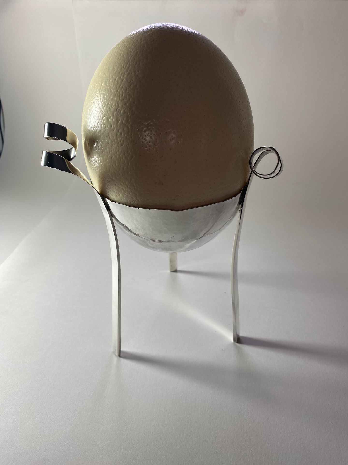 Sterling silver egg cup for an ostrich egg. Bowl hand raised with three legs rising to spirals. Silversmith David Salariya, silver maker,
hand-crafted silver, bespoke silver items, silver artisan, silver workshop.