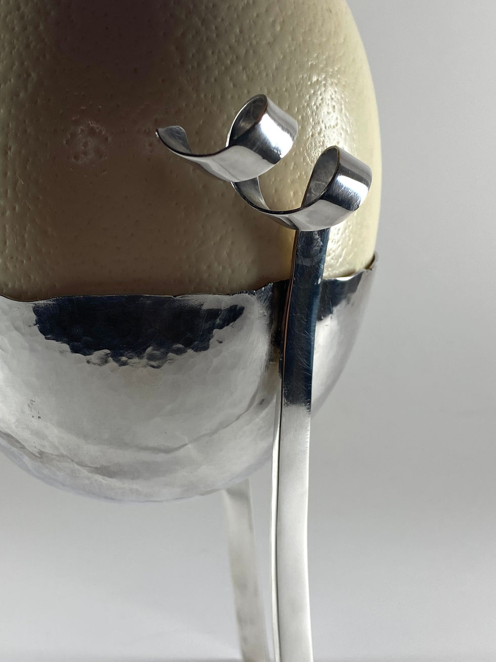Sterling silver egg cup for an ostrich egg. Bowl hand raised with three legs rising to spirals. Silversmith David Salariya, silver maker,
hand-crafted silver, bespoke silver items, silver artisan, silver workshop.