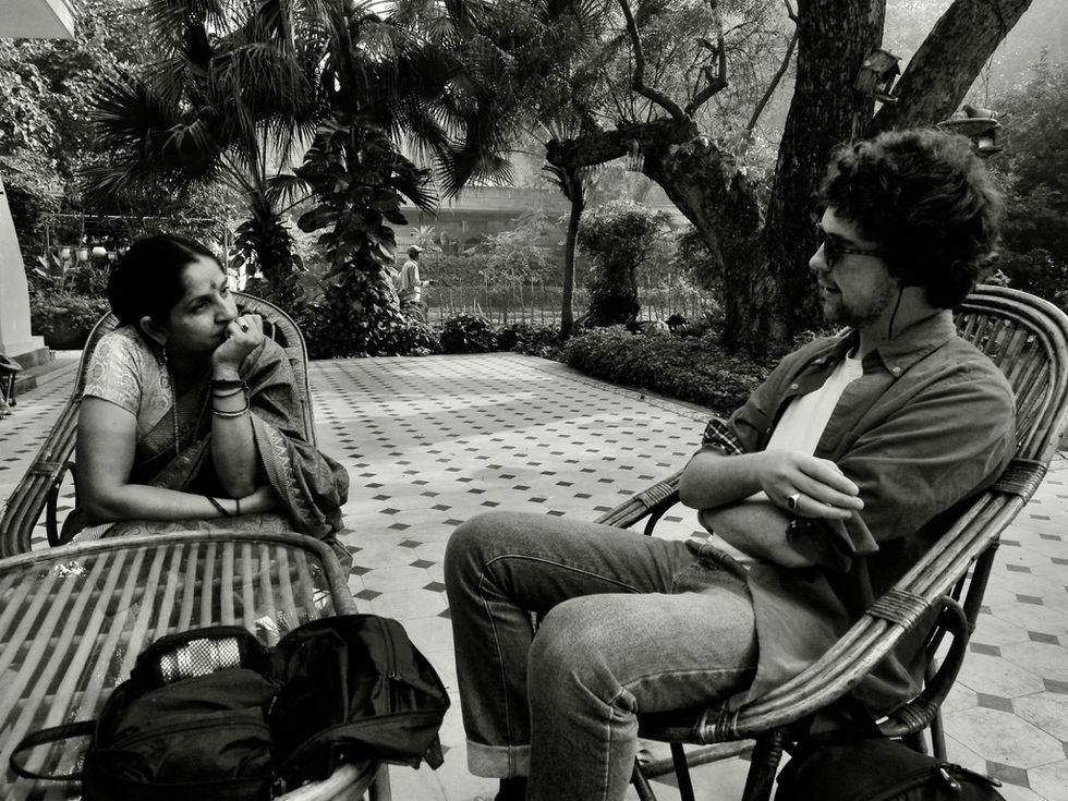 a black and white photo of two people sitting on a patio