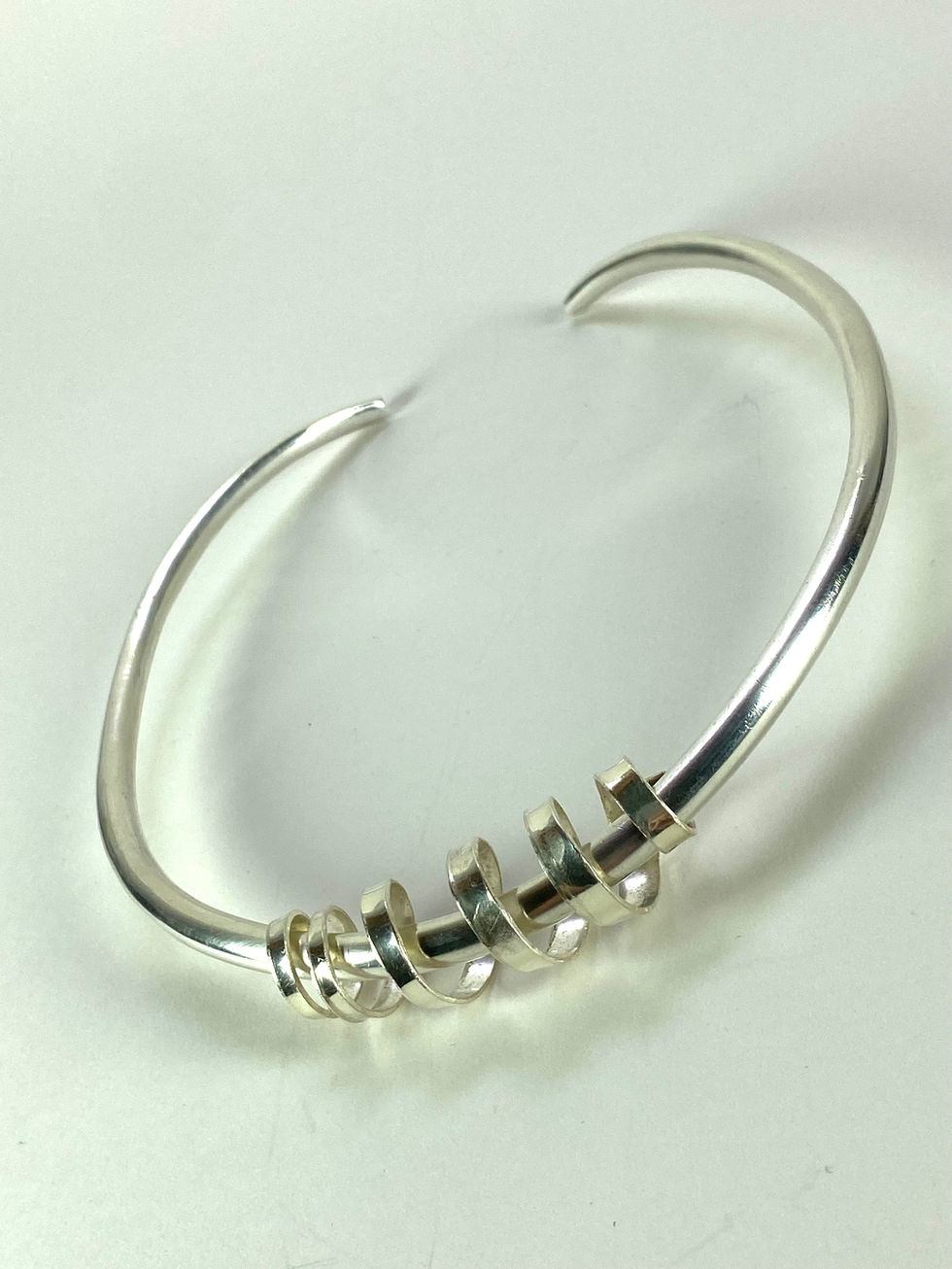 Sterling silver torque with spiral at front. Diamond inserted at each end of torque. Silversmith David Salariya, silver maker,
hand-crafted silver, bespoke silver items, silver artisan, silver workshop.