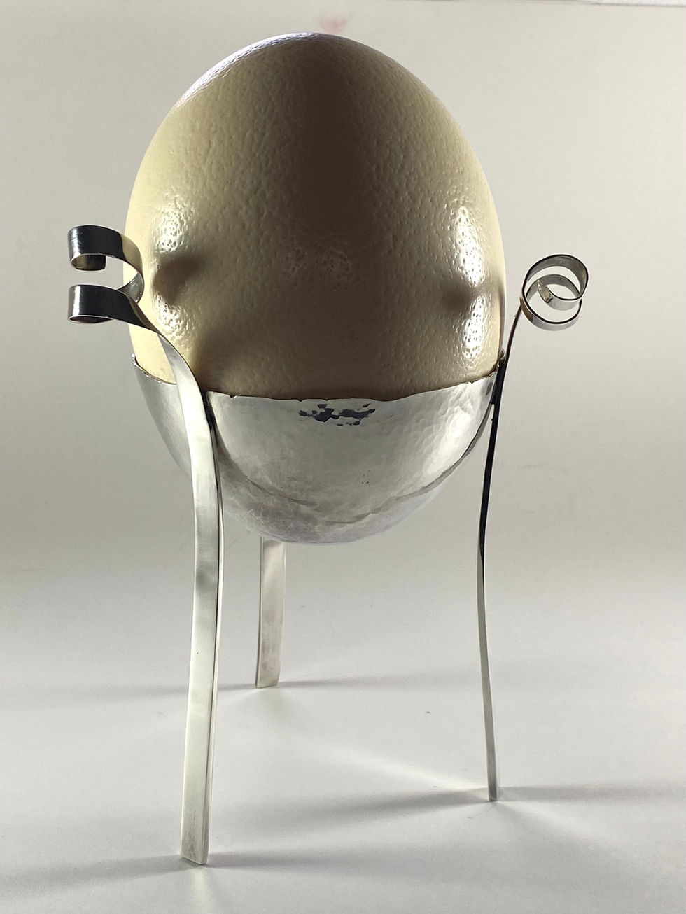 Sterling silver egg cup for an ostrich egg. Bowl hand raised with three legs rising to spirals. Silversmith David Salariya, silver maker,
hand-crafted silver, bespoke silver items, silver artisan, silver workshop.