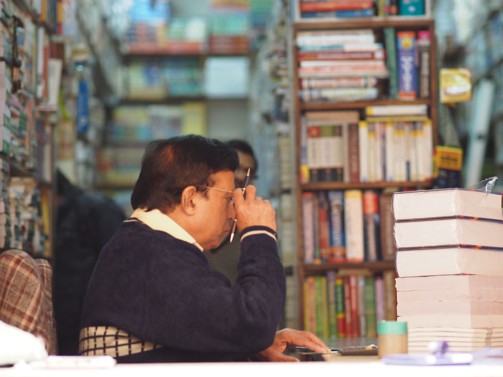 a man wearing glasses is sitting in front of a stack of books