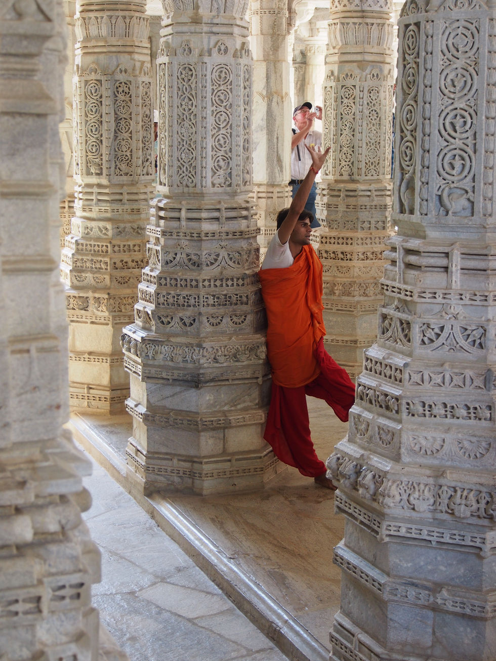 a man taking a picture of a woman leaning against a pillar