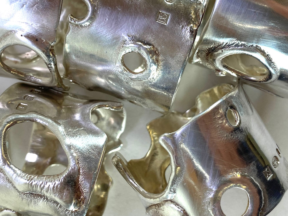 Sterling silver napkins rings, reticulated silver. Silver has 'moon crater' effect created by a technique 'reticulation'. The technique involves heating the silver or gold to up to ten times to oxidise the copper at the surface, then pickling to remove the oxide and leave a thin layer of pure metal on the surface. Silversmith David Salariya, silver maker,
hand-crafted silver, bespoke silver items, silver artisan, silver workshop.