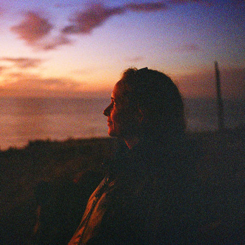 Woman illuminated by the sunset along a coast line.