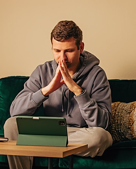 Man looking on the tablet while sitting on his couch Online therapy, mental health.jpg