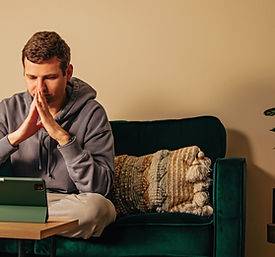 Man looking on the tablet while sitting on his couch Online therapy, mental health.jpg