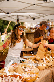 Female vendor handing goods at Garlic Festival.