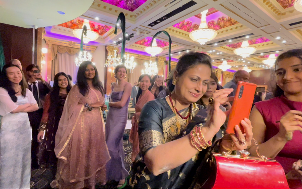 Guests filming on their phones as they watch the live wedding painting process at a South Asian wedding