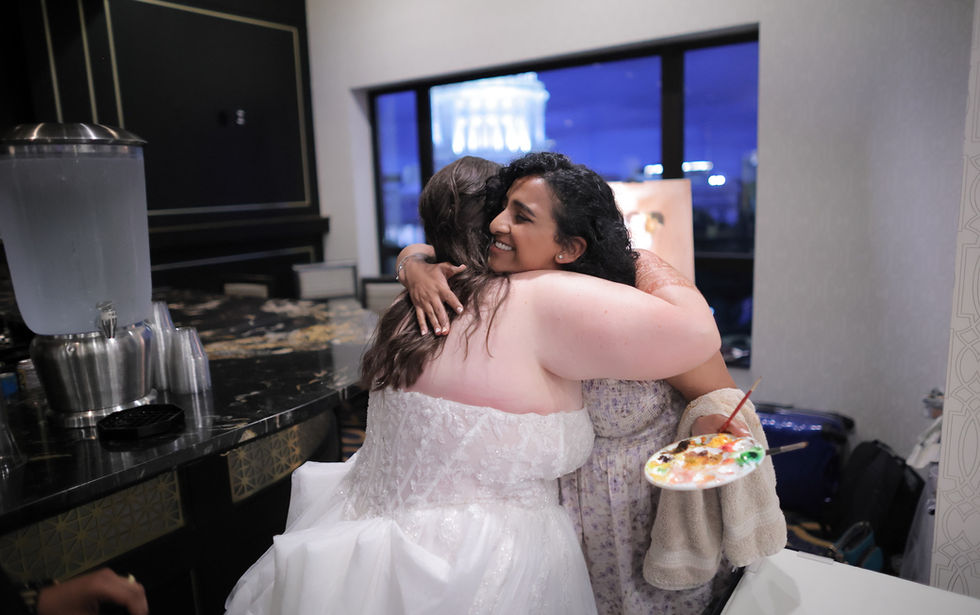 Bride embracing her live wedding painter Renu, palette in hand, at her reception
