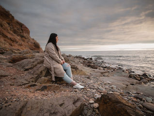 Bree sitting on rocks at beach