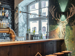 Bar mit Hirsch-Wandbild im Hand aufs Herz