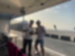 テント内で友人たちと笑顔でボトルを掲げる集合写真。