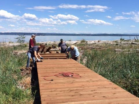 Fairbank Construction crew building a wooden accessibility ramp at Fay Bainbridge Park to provide wheelchair access to the shoreline on a sunny day.
