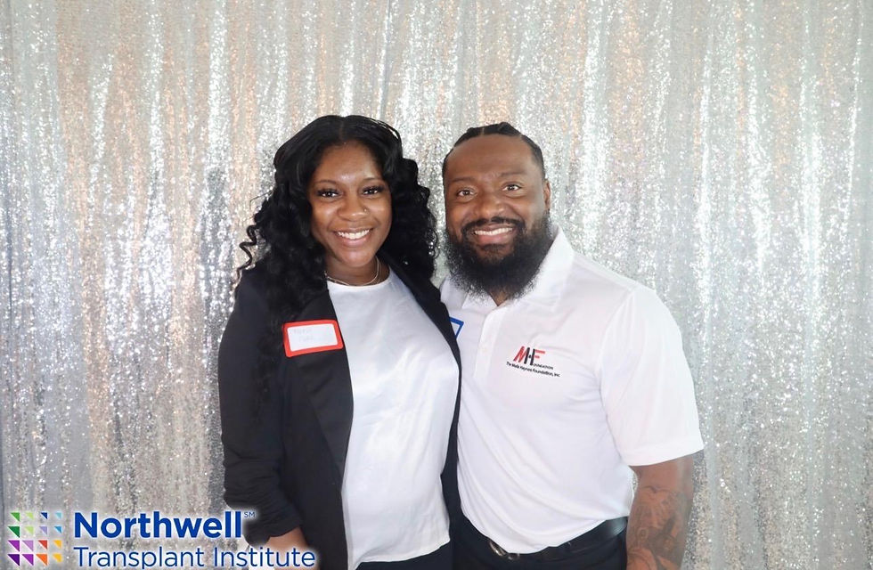 Two people smiling in front of a silver sequin backdrop, landscape photo, bright lighting, community event feel.