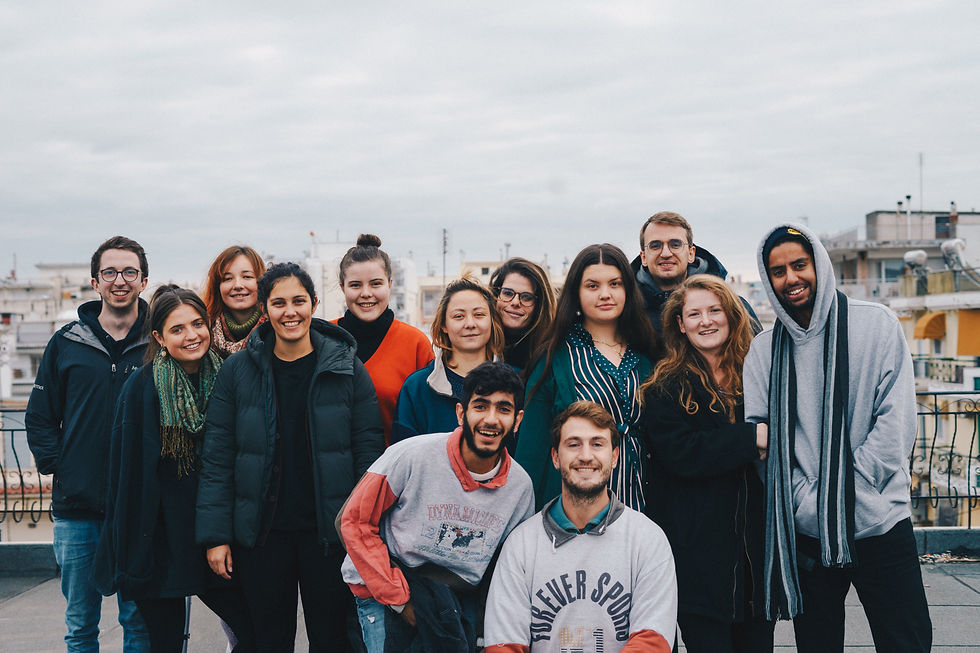 A group of 13 volunteers are smiling at the camera, dressed in warm clothing