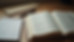 Close-up view of a Bible open to Acts with a notebook and pen nearby